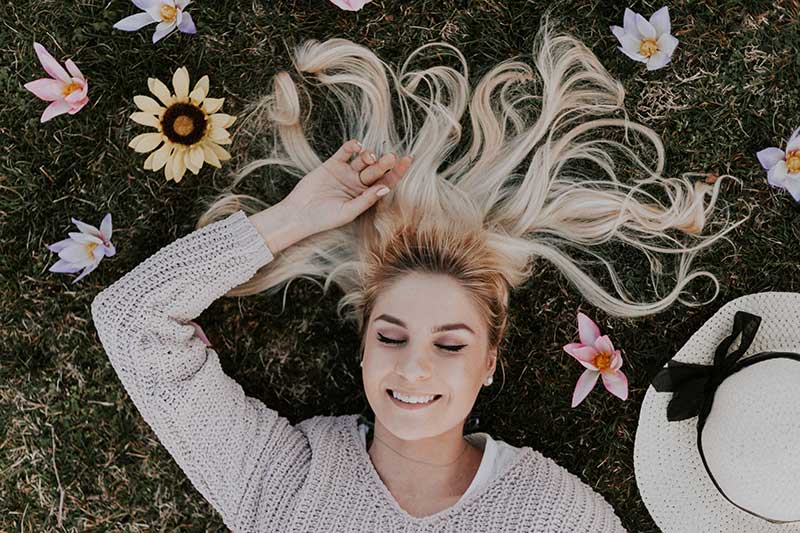 A woman laying on the ground with flowers around her hair
