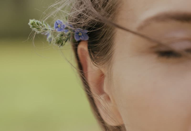 A person with a flower over their ear.