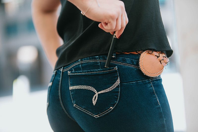A person putting a pen in the back pocket of their jeans