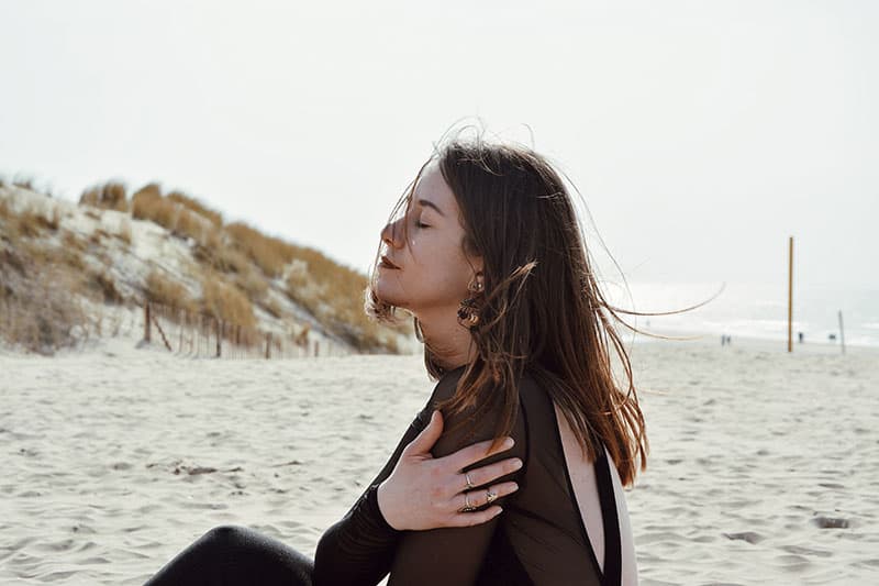 A woman sitting on the beach looking up