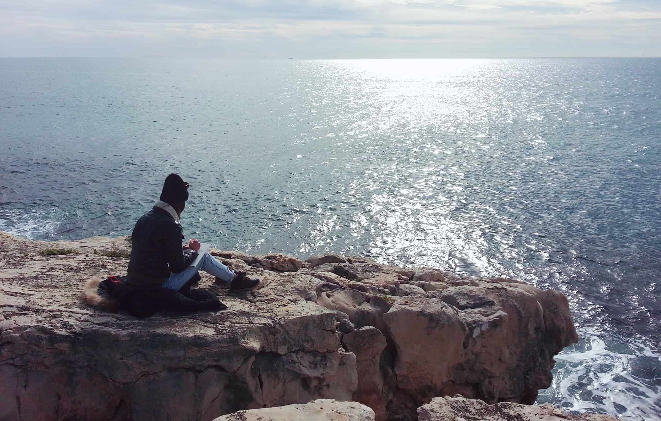 Person sitting on a rock overlooking water