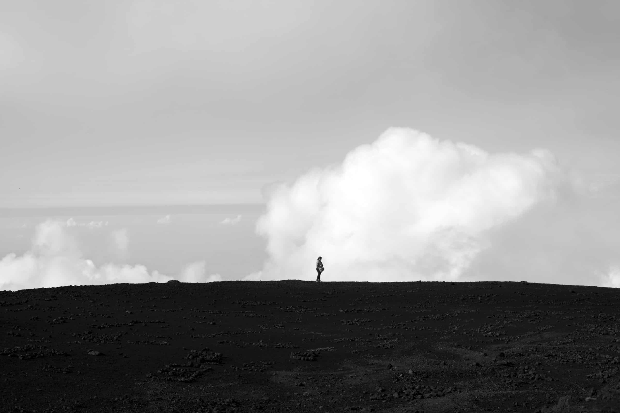Person standing outside with clouds in the background.